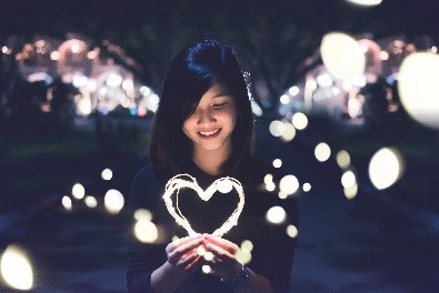 A girl holding a light heart at night